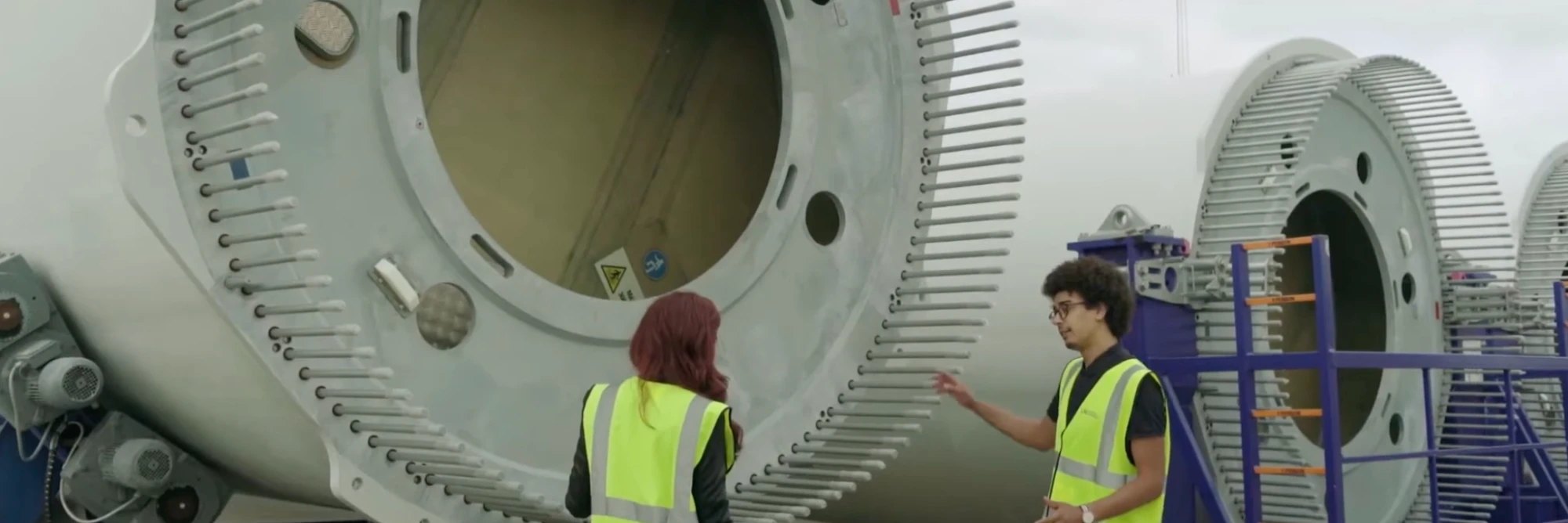 Explaining a blade root and its bolt flange to a colleague at a blade yard