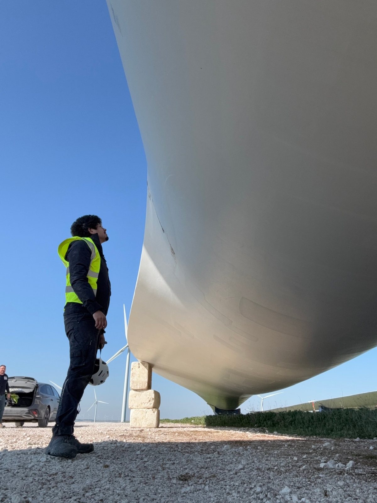 Examining a wind turbine blade resting on stands at a wind farm