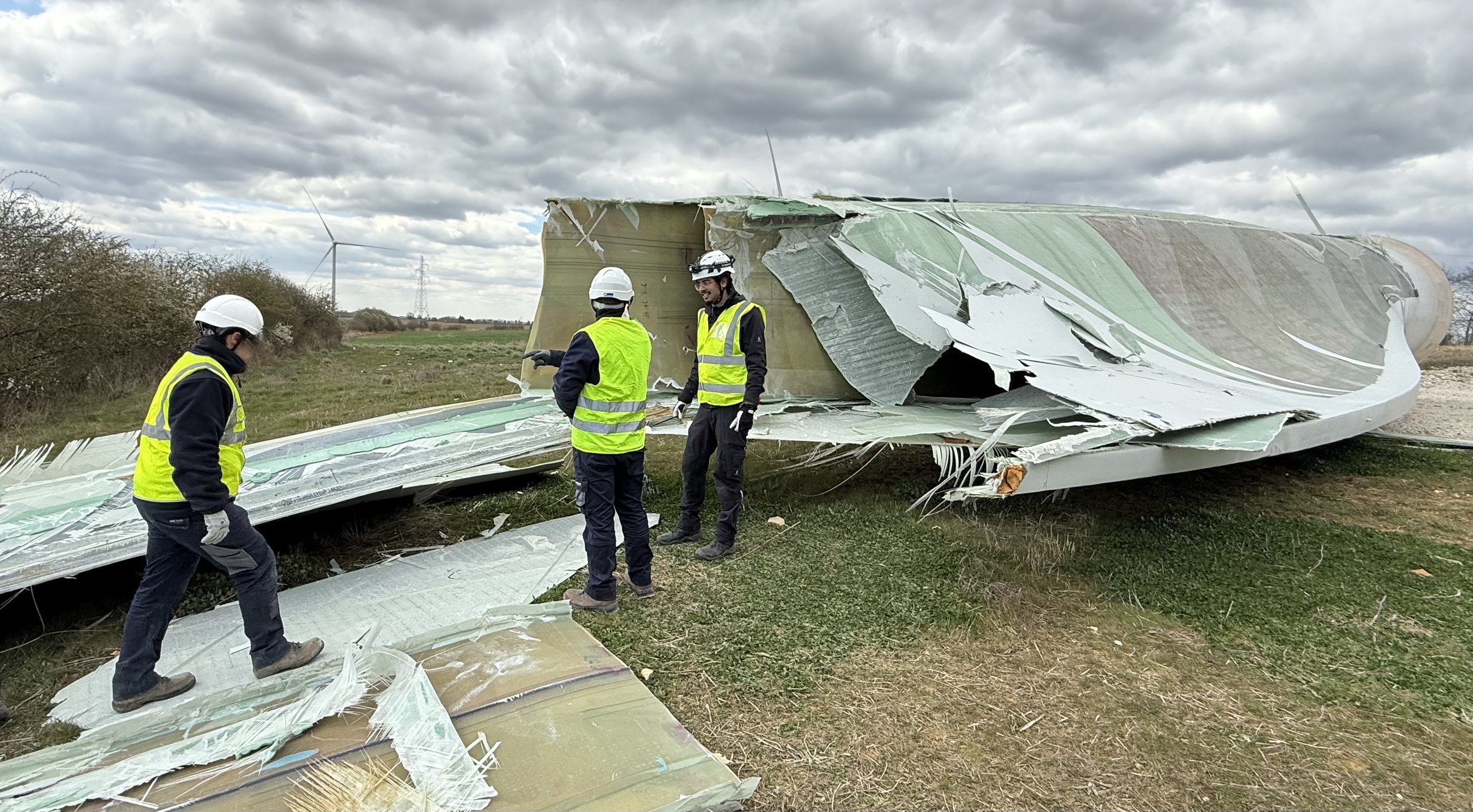 Engineers examining a wind turbine blade that has ruptured and come down in a field